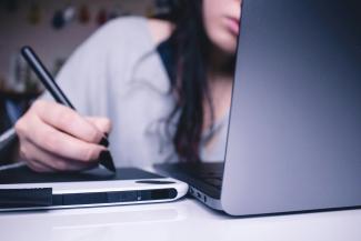 woman using drawing pad while sitting in front of laptop by Josefa nDiaz courtesy of Unsplash.